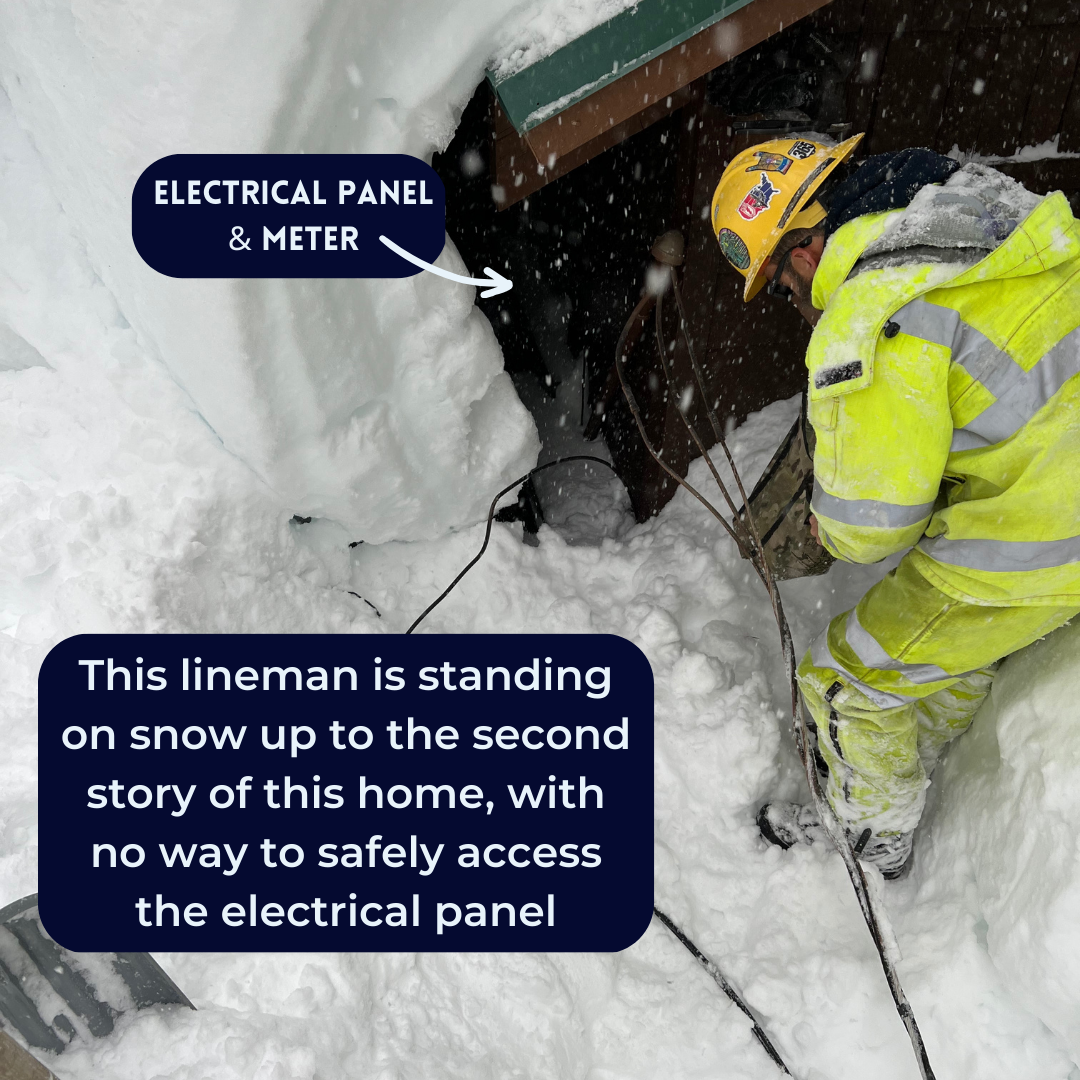 Lineman standing on snow bank looking down into hole where electrical panel is