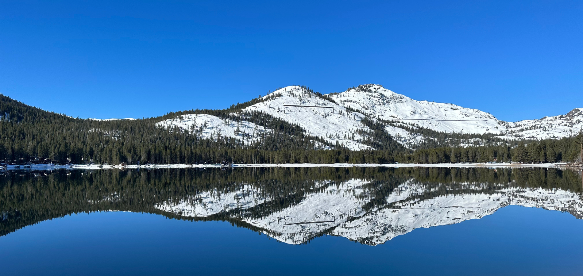 donner lake snowy peaks with reflection on still lake surface